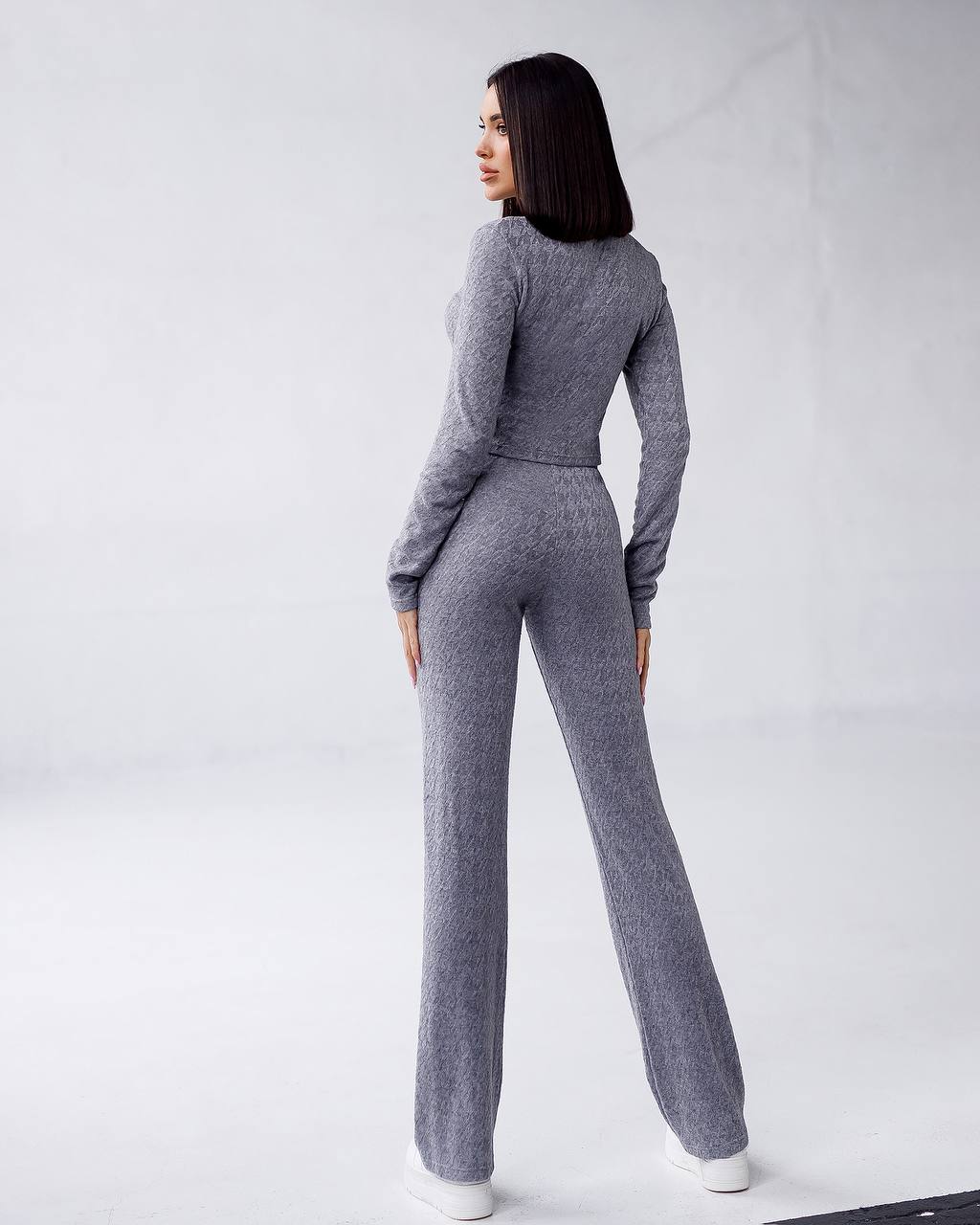 Woman wearing a gray knit outfit on a white background