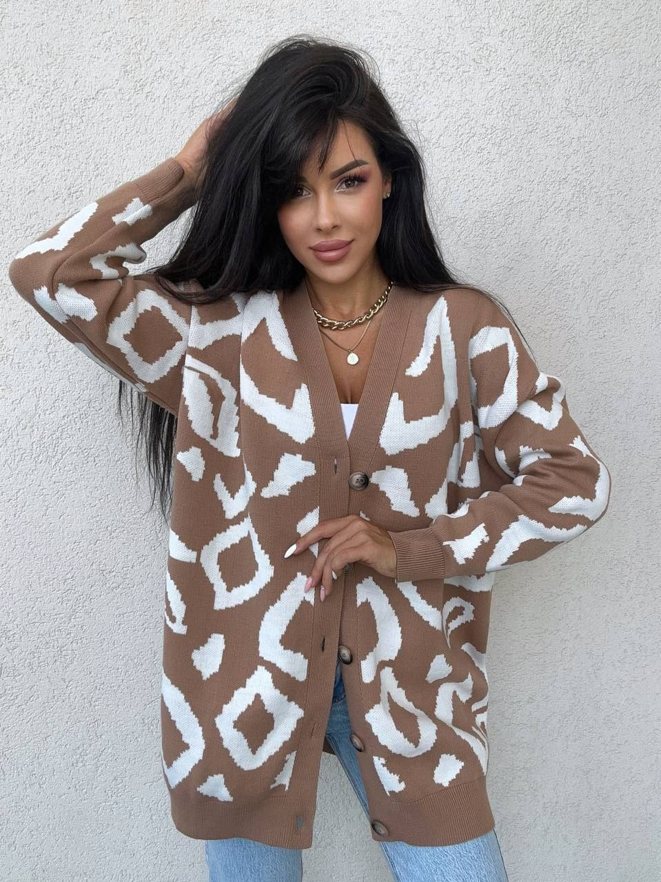 Woman wearing a brown and white patterned cardigan against a plain background