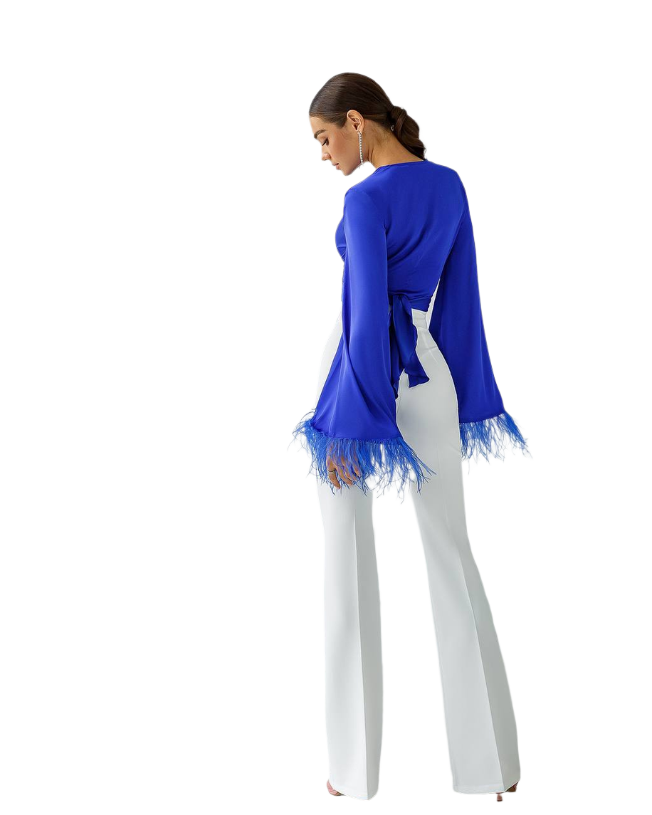 Woman wearing a blue top with lace trim and white pants on a white background