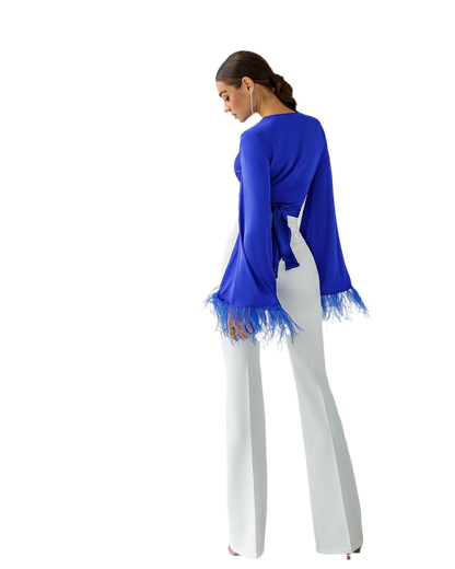 Woman wearing a blue top with lace trim and white pants on a white background