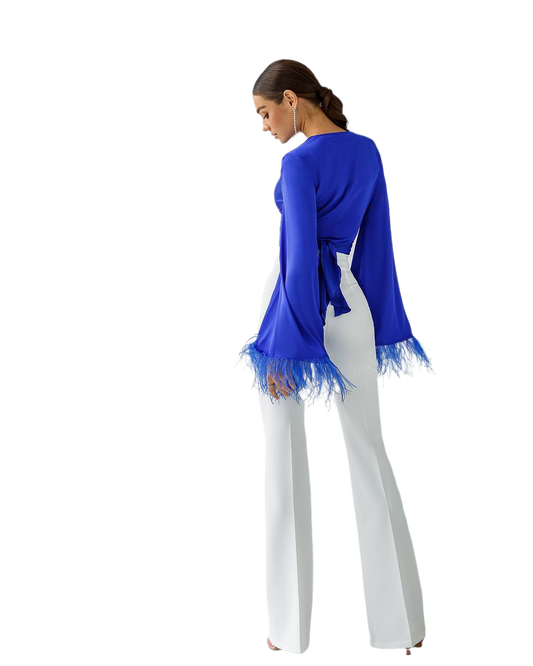 Woman wearing a blue top with lace trim and white pants on a white background