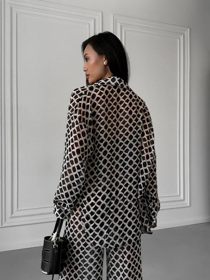 Woman wearing a patterned dress against a white wall