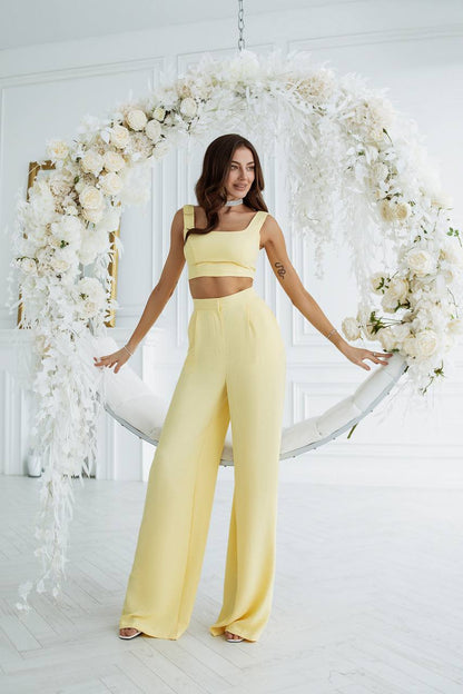 Woman in a yellow outfit standing in front of a floral arch