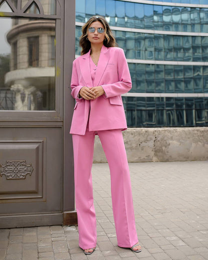 Woman in a pink suit standing in front of a modern building.