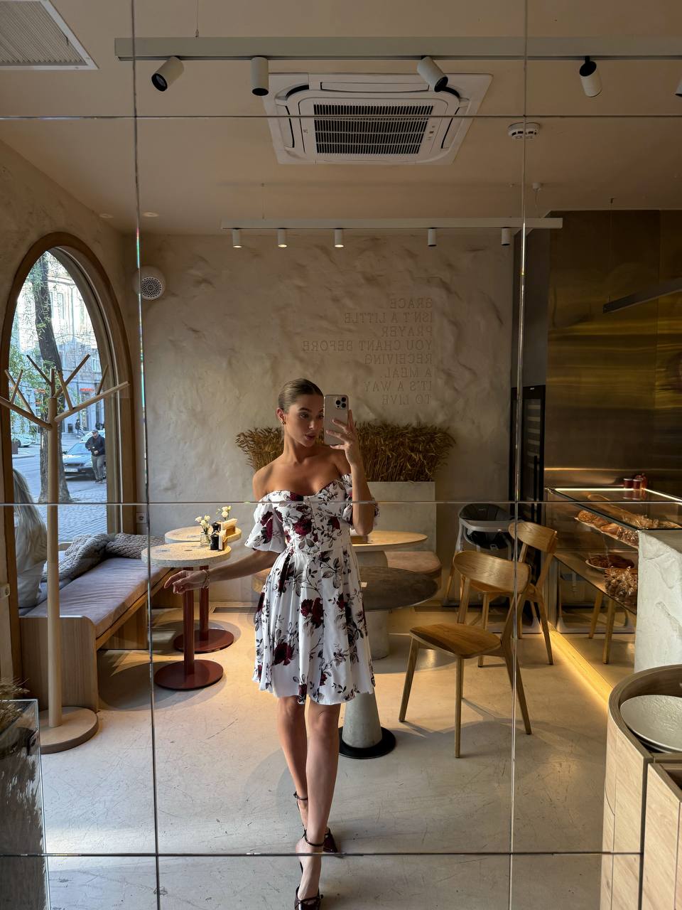 Person taking a mirror selfie in a modern cafe.