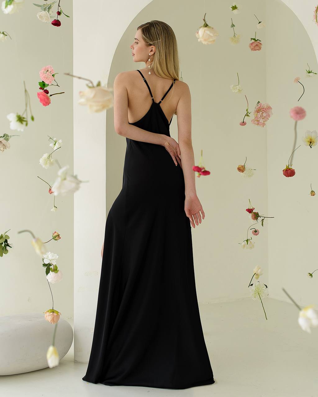 Woman in a black dress standing in a room with floral decorations.