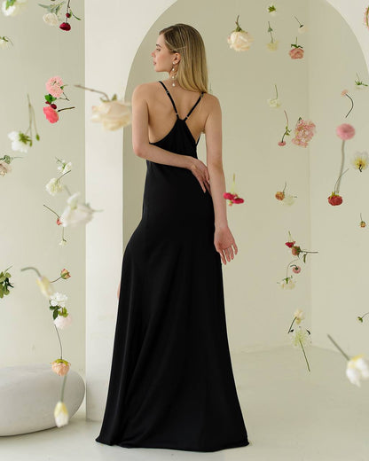 Woman in a black dress standing in a room with floral decorations.