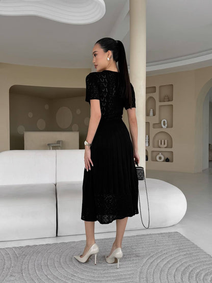 Woman in a black dress standing in a modern interior setting