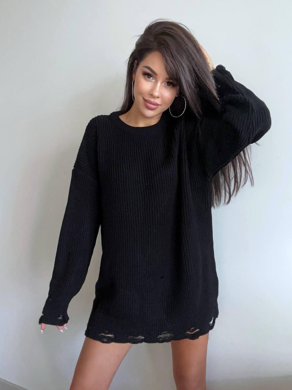 Woman wearing a black sweater dress against a plain background