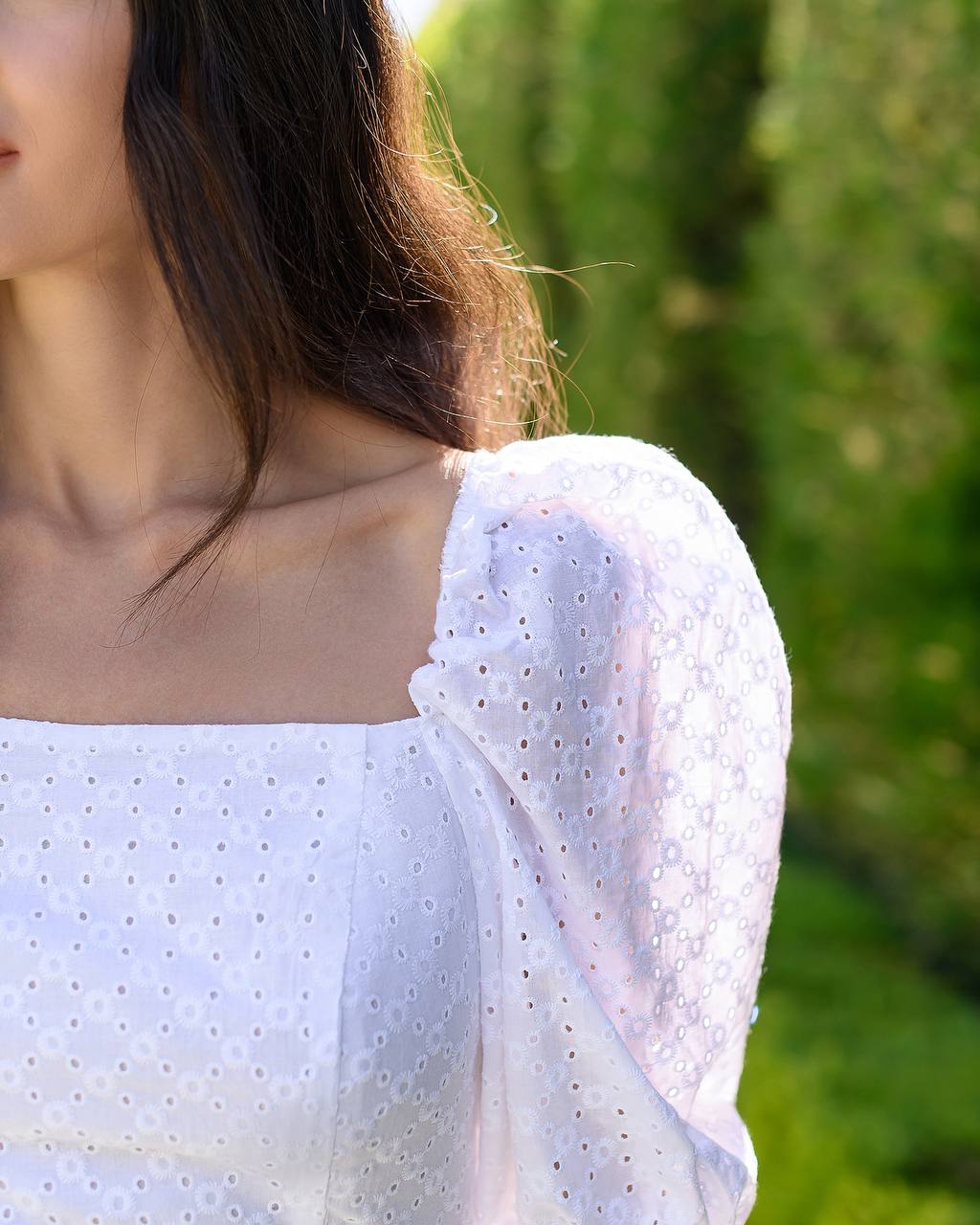 Person wearing a light blue blouse with a blurred green background