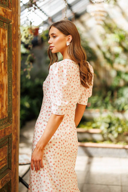 Woman in a floral dress standing in a greenhouse