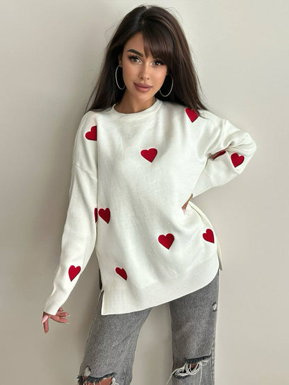 Woman wearing a white sweater with red heart patterns on a plain background