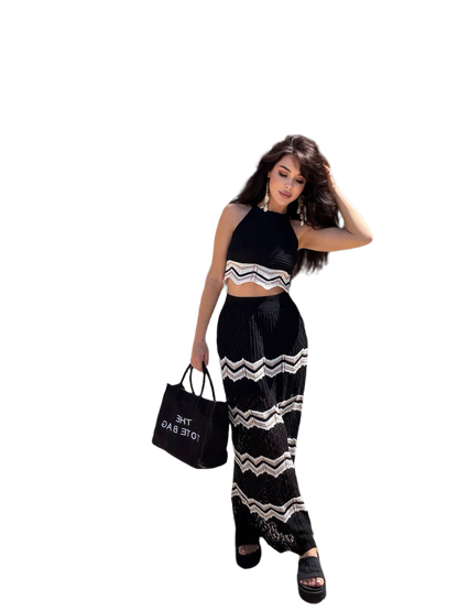 Woman wearing a black and white outfit with a zigzag pattern, holding a black handbag.