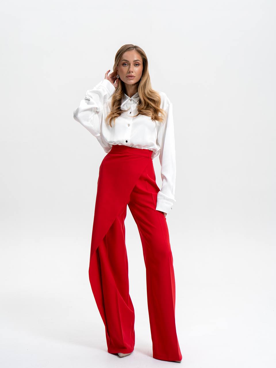 Woman wearing a white blouse and red pants on a white background