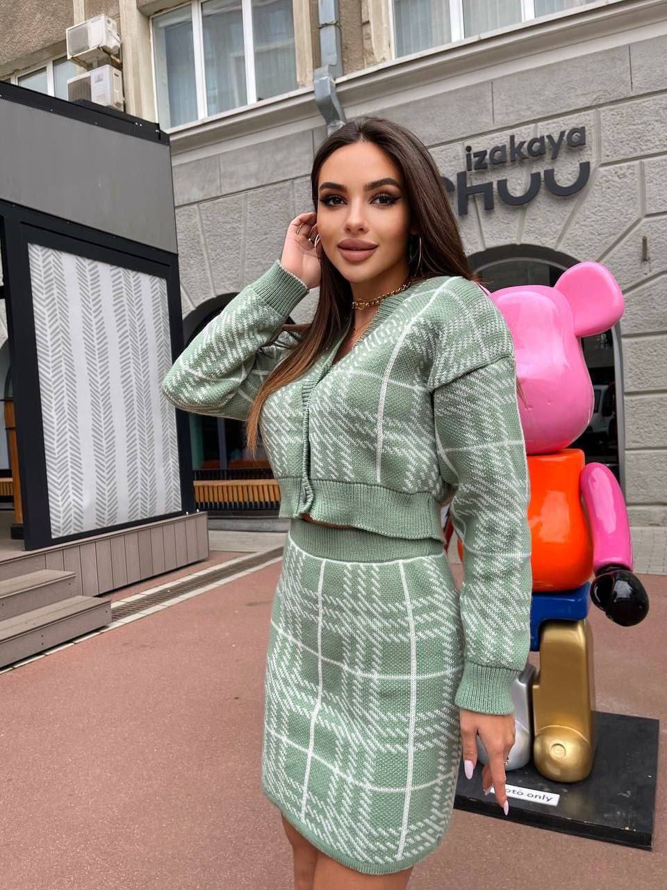 Woman in a green dress standing in front of a building with colorful sculptures.