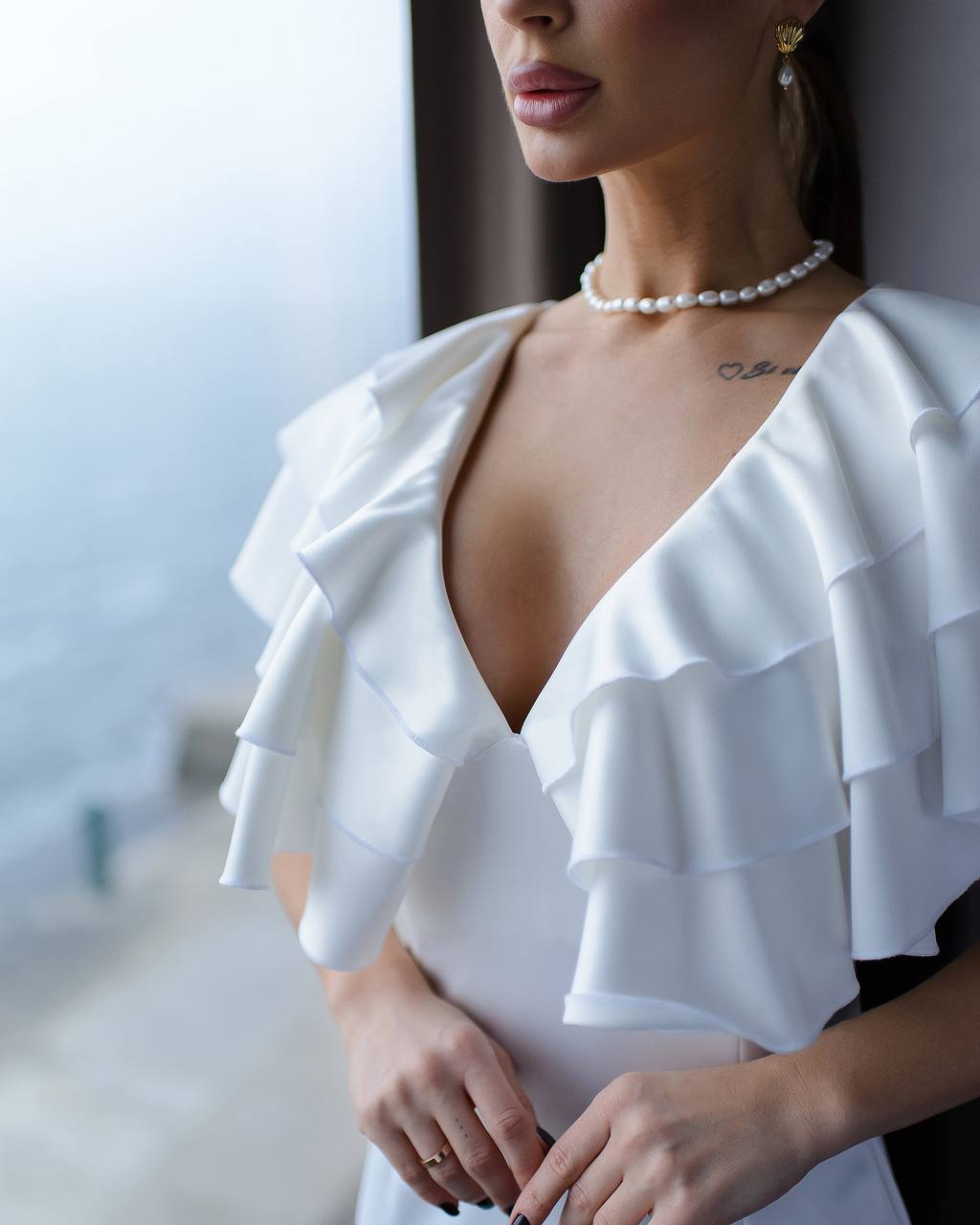 White ruffled top worn by a person, with a blurred background