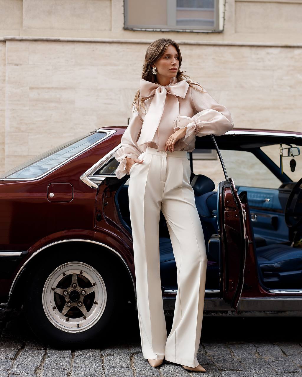 Woman in a stylish outfit standing next to a vintage car