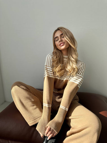 Woman wearing a beige and white striped sweater sitting on a brown chair.