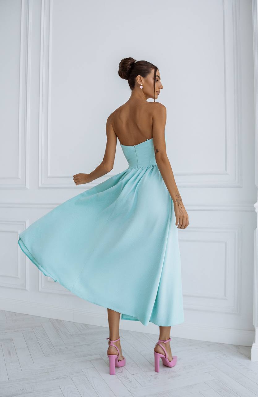 Woman wearing a light blue dress with a white wall background