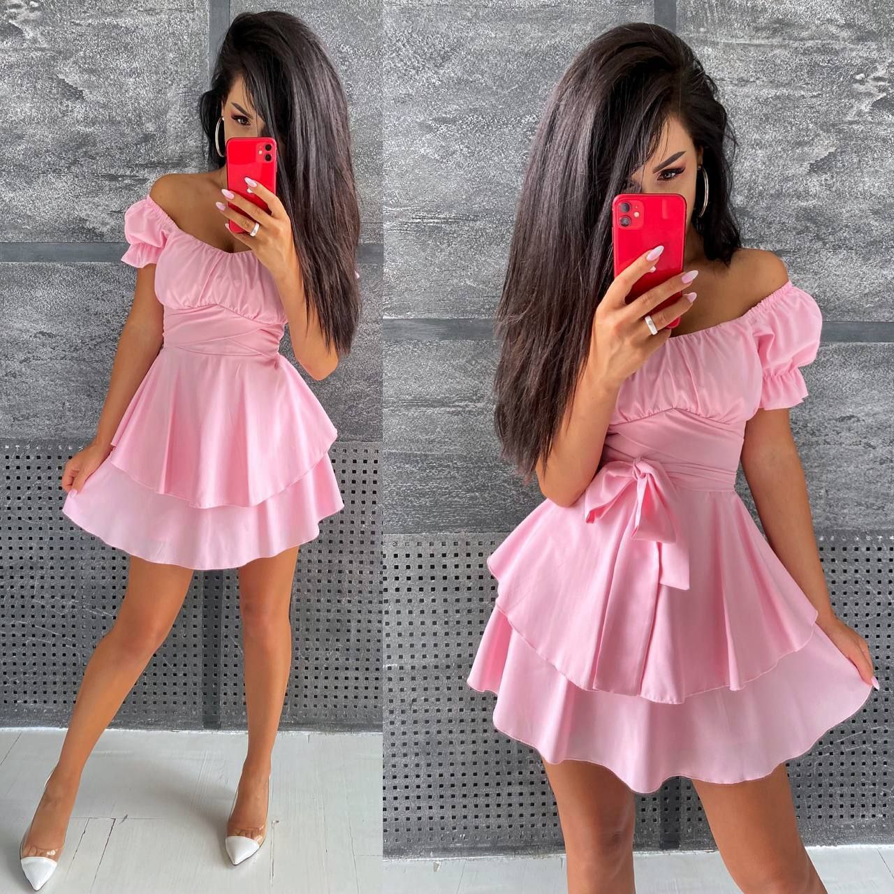 Woman wearing a pink dress taking a mirror selfie against a gray wall.