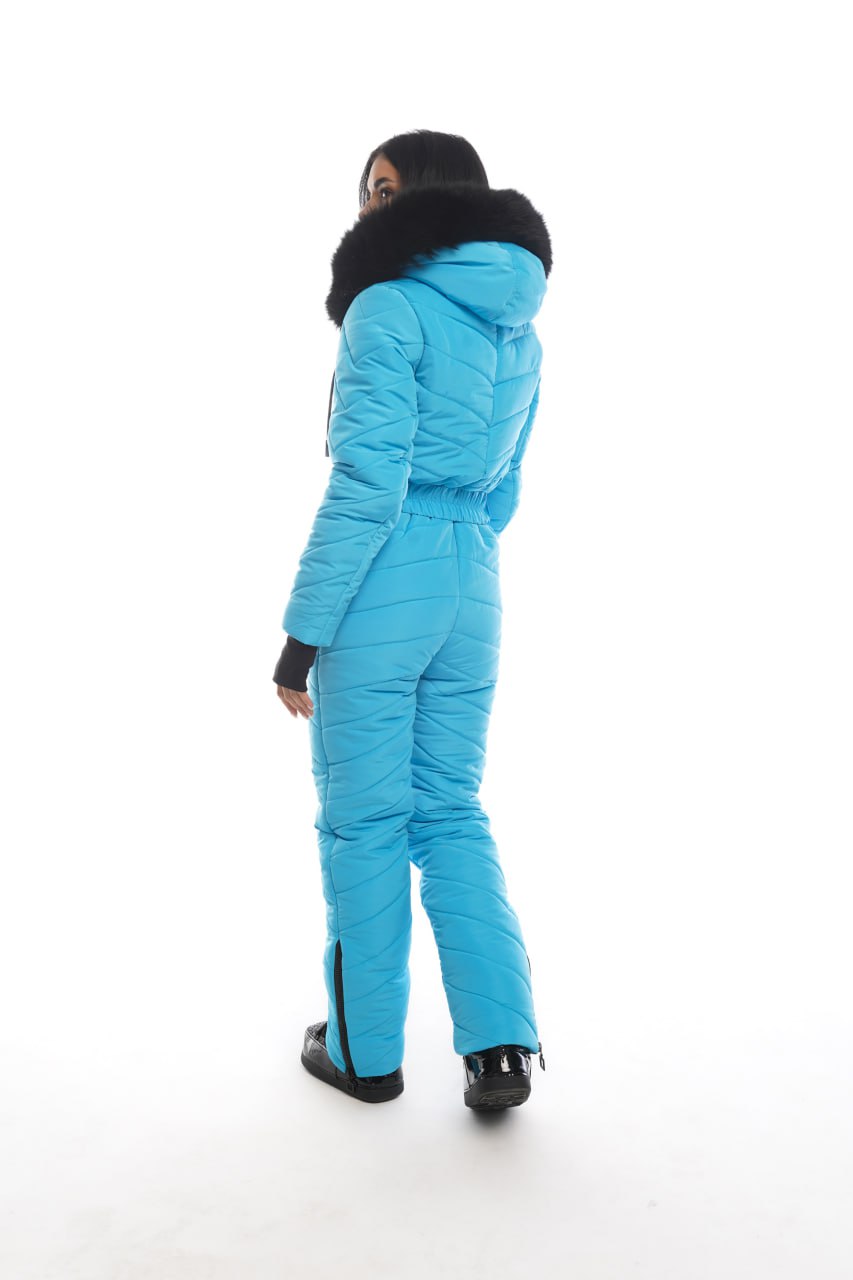 Person wearing a blue snowsuit with black accents on a white background