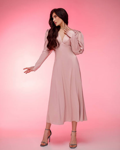 Woman wearing a pink dress with long sleeves against a pink background
