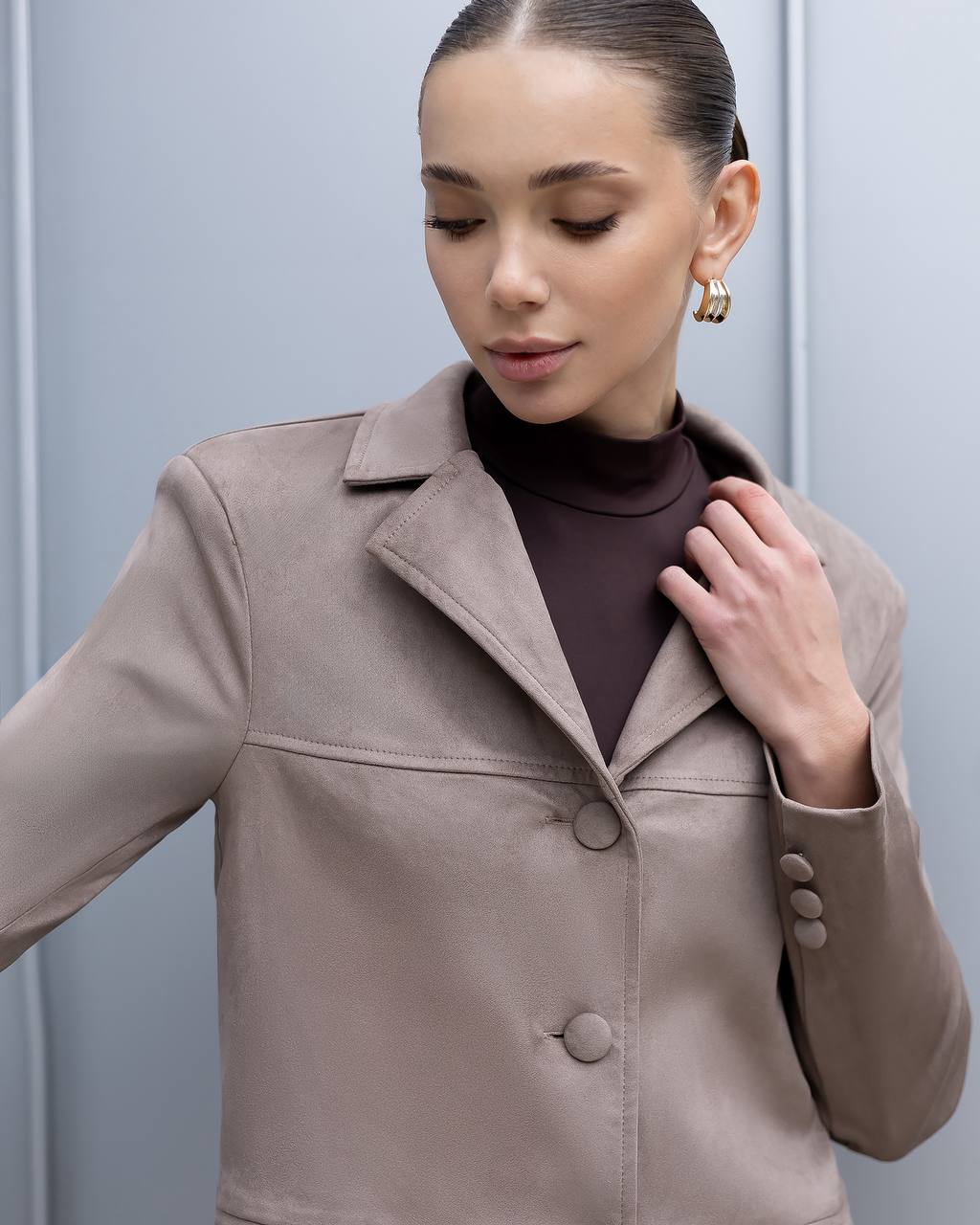 Woman wearing a beige coat against a light gray background