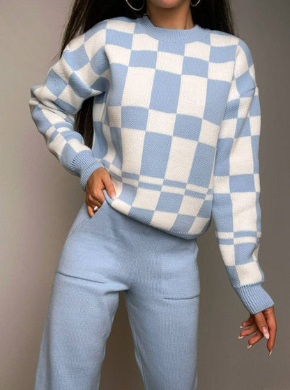 Person wearing a blue and white checkered sweater and pants against a gray background