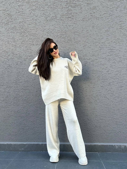 Woman in a white outfit posing against a gray wall