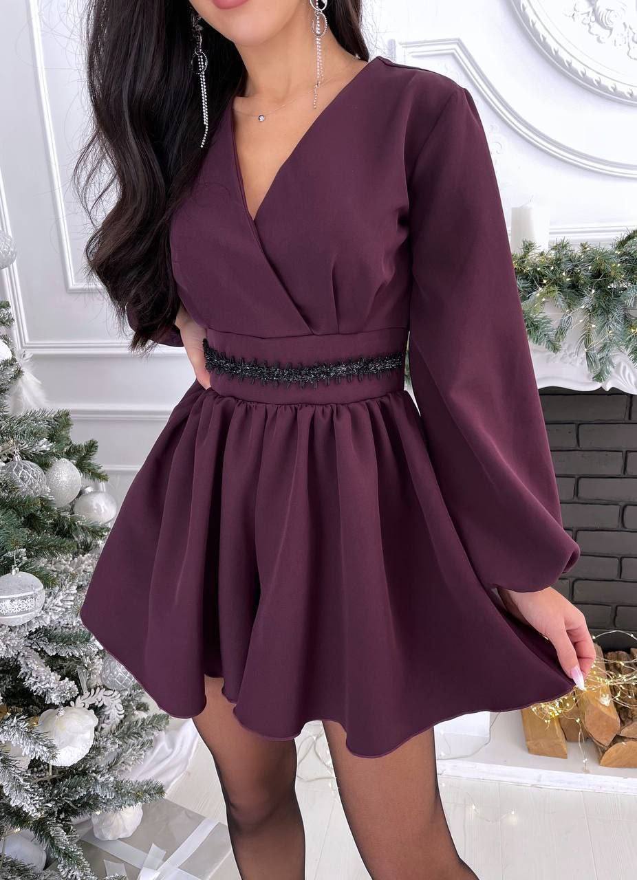 Woman wearing a burgundy dress with long sleeves in a festive indoor setting.