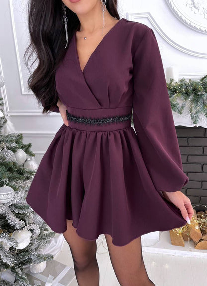 Woman wearing a burgundy dress with long sleeves in a festive indoor setting.