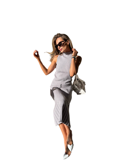 Woman in a gray dress with sunglasses and a handbag on a white background