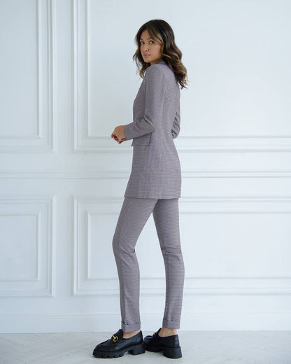 Woman wearing a gray checkered suit against a white paneled wall