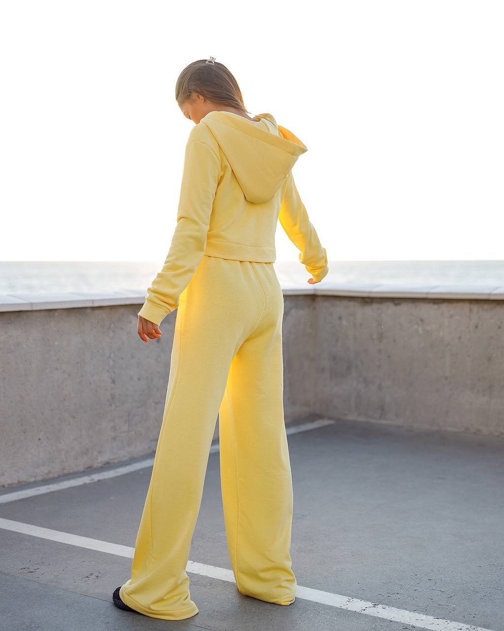 Person wearing a yellow tracksuit on a rooftop.