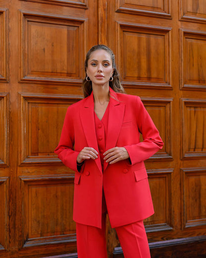 Woman wearing a red suit standing in front of a wooden door