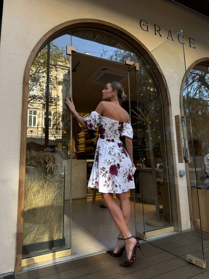 Woman in a floral dress standing outside a building with 'GRACE' on the door.