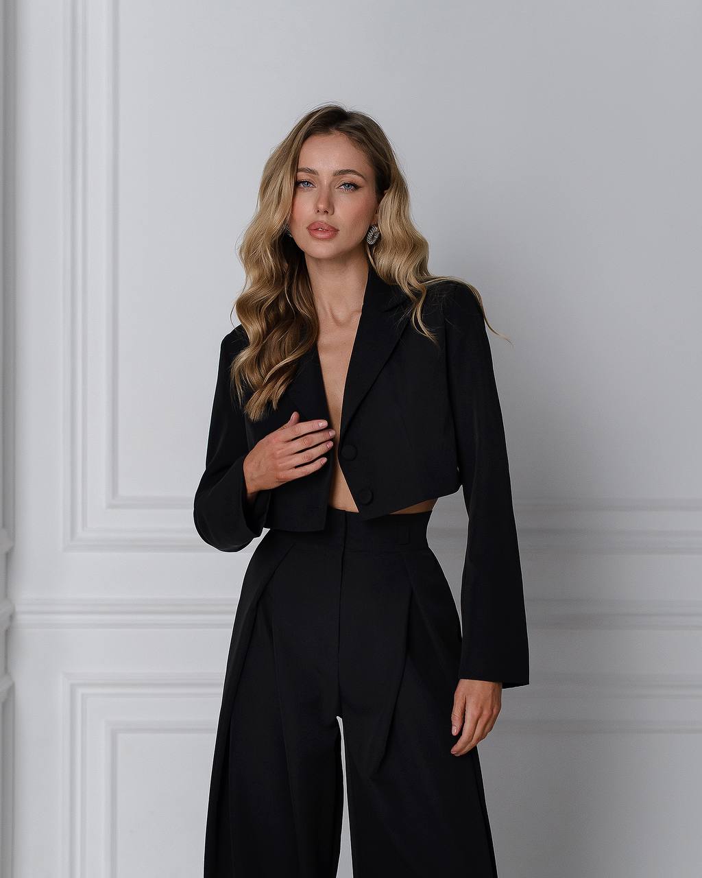 Woman wearing a black suit against a gray wall