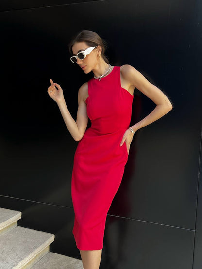 Woman in a red dress posing against a black wall