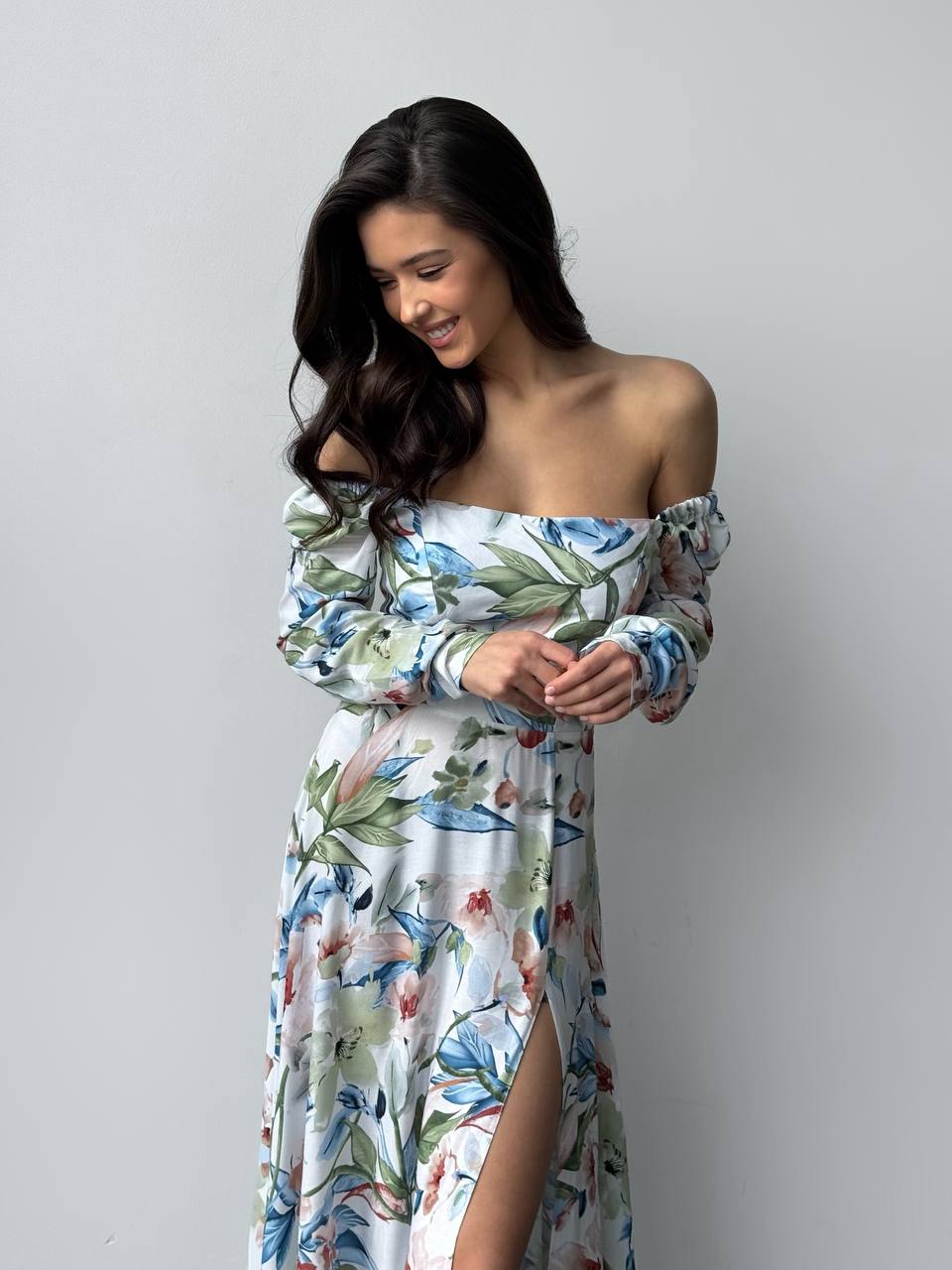 Woman wearing a floral off-shoulder dress against a plain background