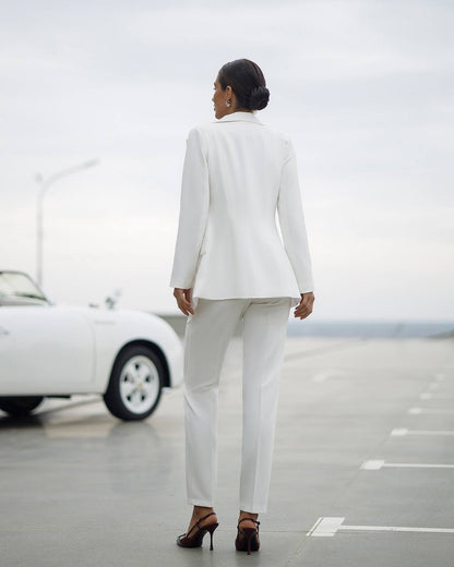 Person wearing a white suit standing on a road with a car in the background