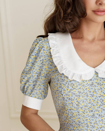 Close-up of a floral dress with white ruffled collar and cuffs.