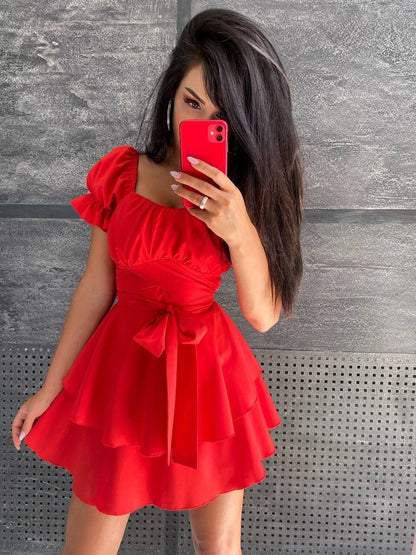 Woman in a red dress taking a selfie against a gray textured wall