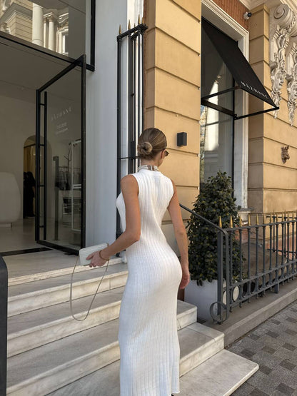 Woman in a white dress entering a building with a stylish exterior.
