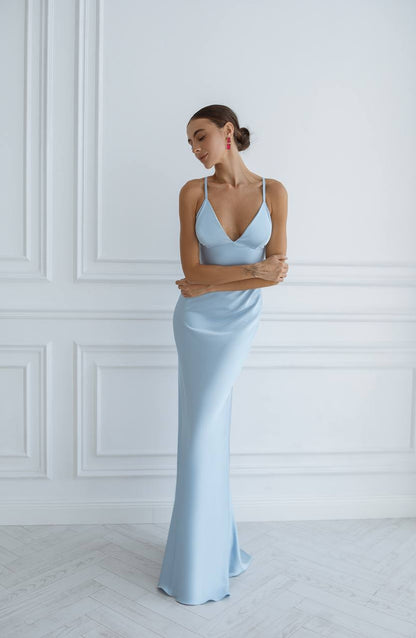 Woman wearing a light blue evening gown against a white wall.