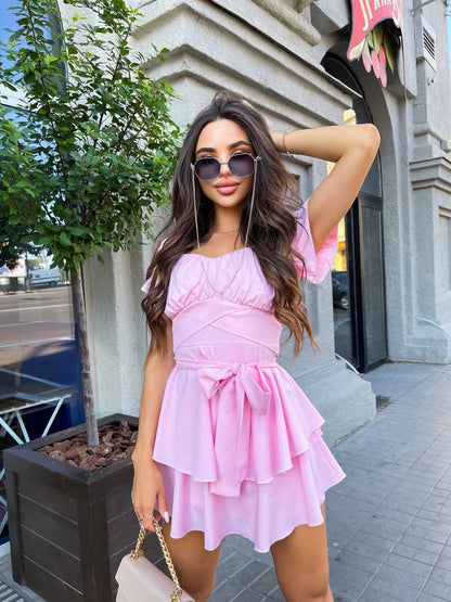 Woman in a pink dress posing on a city street.