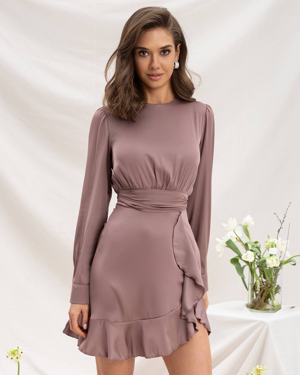 Woman wearing a mauve long-sleeve dress with a white background