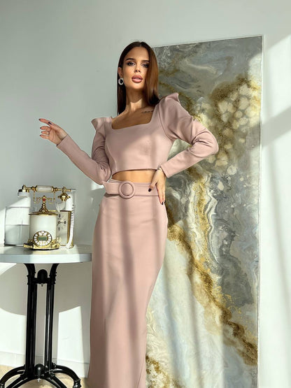 Woman in a pink outfit standing next to a decorative wall piece