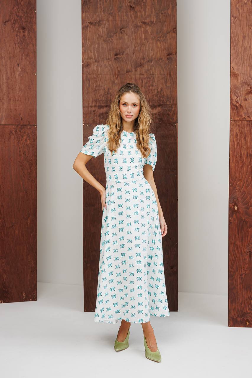 Woman wearing a patterned dress standing against a wooden background