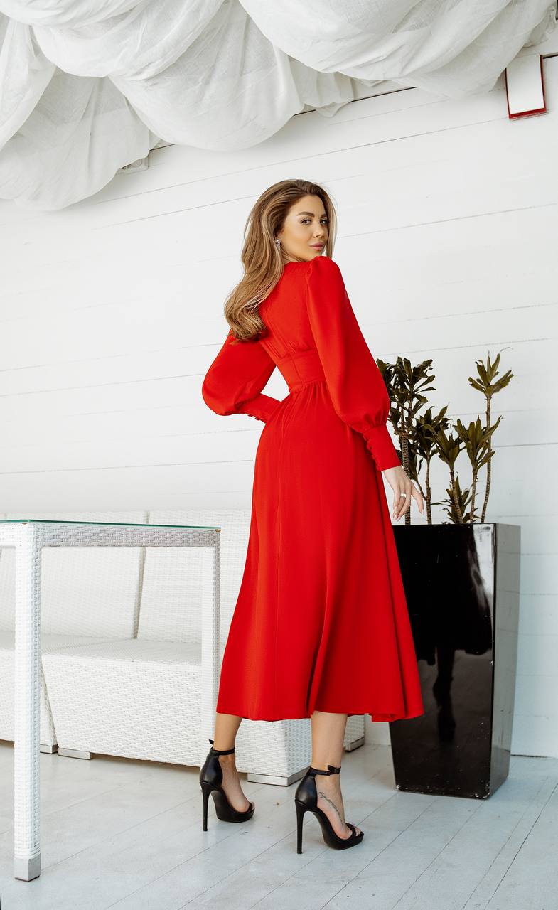 Woman in a red dress standing in a modern interior setting with white walls and minimal decor.