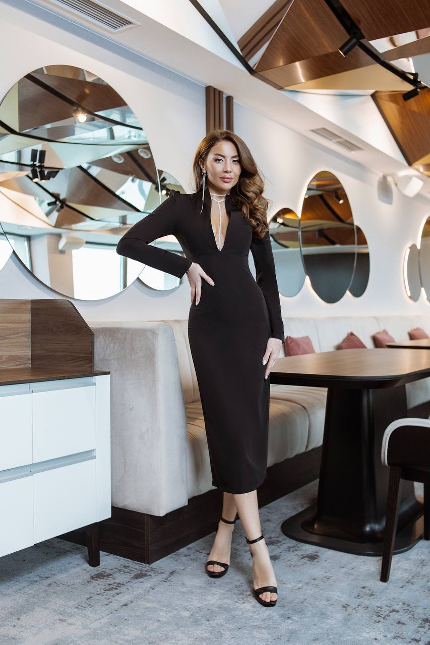 Woman in a black dress posing in a modern restaurant setting